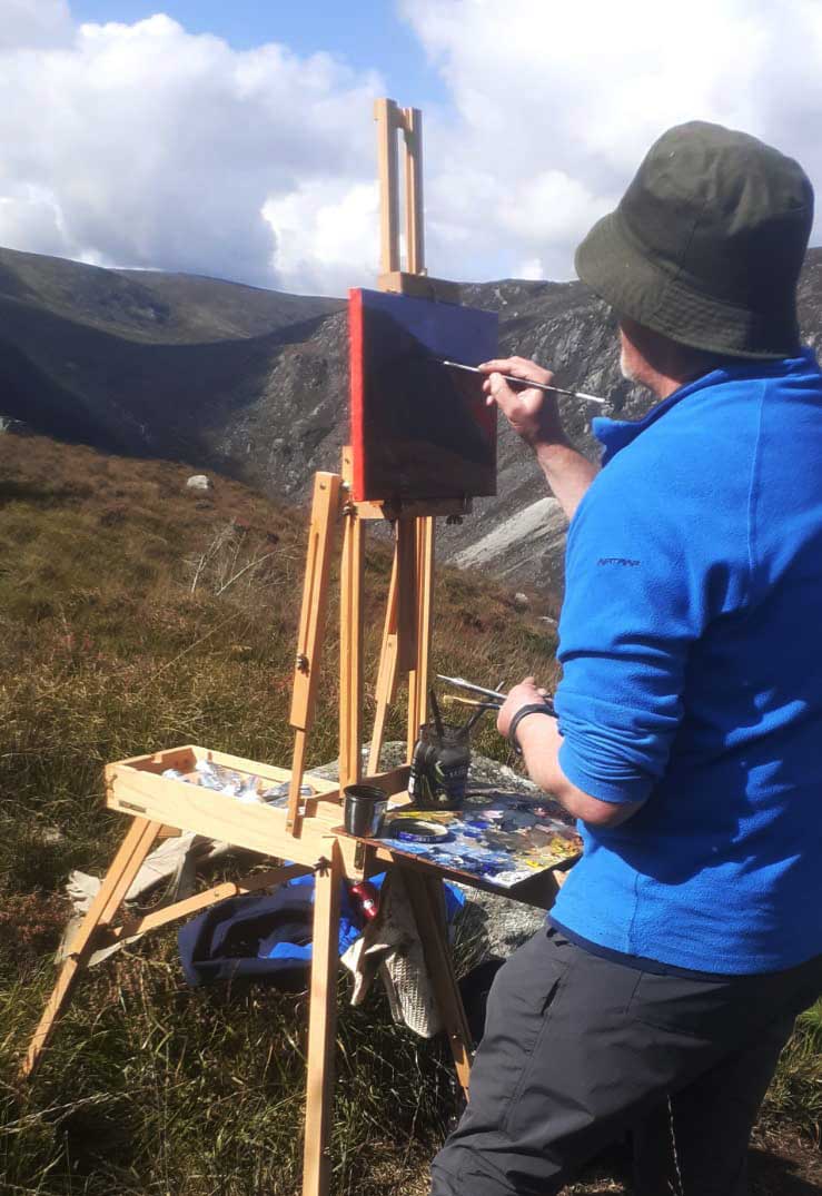 The artist Kieran Guckian at work painting on the Spinc Glendalough